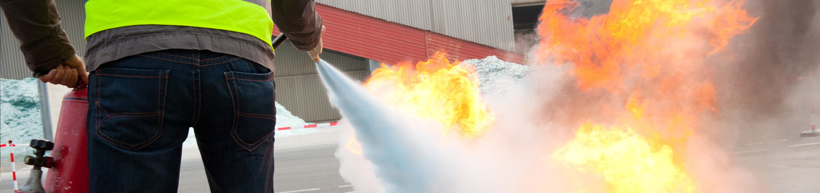 Ein Brandschutzhelfer löscht eine Flamme mit einem Feuerlöscher.