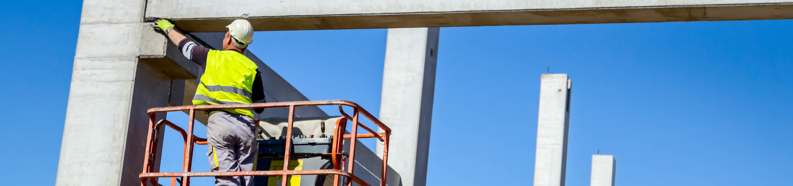 Ein Arbeiter steht auf einem Teleskopstapler auf einer Baustelle